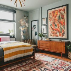 a bed sitting in a bedroom next to a window with a painting on the wall