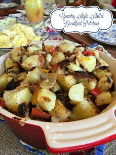 a red bowl filled with potatoes and other food items on top of a blue and white table cloth