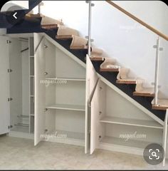 an empty room with some shelves under the stairs and a closet underneath the stair case