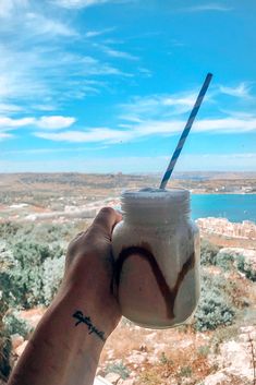 a hand holding a drink with a blue and white straw sticking out of it's top