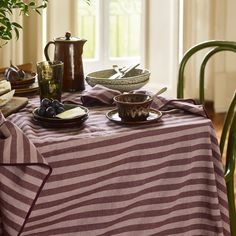 a table topped with plates and bowls next to a potted plant