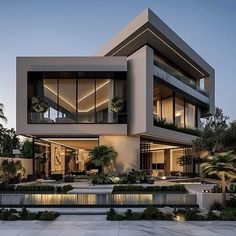 a large modern house with lots of windows and plants on the front lawn at dusk