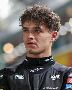 a close up of a person wearing a racing suit and looking off to the side