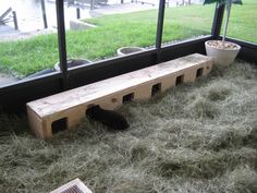 a wooden bench sitting next to a window in a room filled with hay and grass