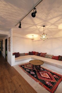 a living room filled with lots of furniture next to a wall mounted light above a coffee table