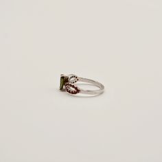 Unleash cosmic energy with our Moldavite and Garnet Ring, elegantly crafted in sterling silver. Each ring pairs a pear-shaped Moldavite with bezel-set pavé Garnet stones. Experience profound transformation and growth as these gems work to guide you towards spiritual clarity and inner peace. Key Benefits & Features: Striking Combination: Features a vibrant pear-shaped Moldavite stone paired with striking Garnet stones, set in polished sterling silver. Energetic Synergy: Moldavite, known for its transformative power, is complemented by Garnet's properties of passion and protection, enhancing overall vibrational impact. Perfect Fit: Offered in a sizes 6, 8, 9, and 10. Gemstone Properties: Moldavite: This rare gemstone, formed by a meteorite impact, is renowned for its abilities to accelerate Silver Teardrop Ring With Center Stone, Sterling Silver Teardrop Jewelry With Center Stone, Elegant Silver Teardrop Emerald Ring, Elegant Teardrop Emerald Ring In Silver, Formal Teardrop Tourmaline Jewelry, Silver Tourmaline Promise Ring, Sterling Silver Rings With Pear-shaped Center Stone, Silver Pear-shaped Jewelry With Accent Stones, Silver Ruby Ring With Gemstone Accents For Promise