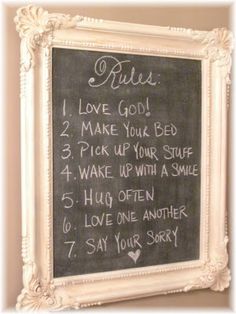 a chalkboard with rules written on it in front of a white framed sign that says rules i love you make your bed, pick up your stuff, wake up with a smile, hug, hug, hug, hug,