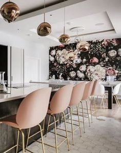 an elegant kitchen with pink chairs and floral wallpaper on the walls, along with marble countertops