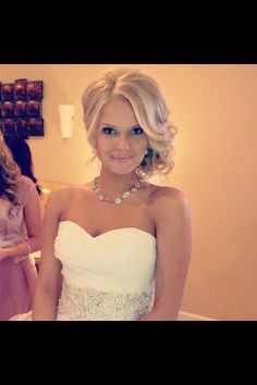 a woman in a strapless white dress posing for a photo with her wedding jewelry