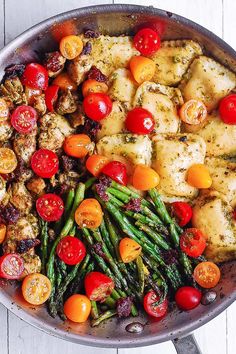 a pan filled with chicken, tomatoes and asparagus