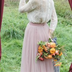 a woman in a long pink skirt holding flowers