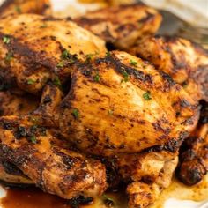 grilled chicken on a plate with sauce and parsley