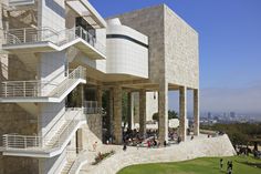 people are walking around in front of a building with many balconies and stairs