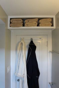 there are many towels hanging on the shelf above the door and in front of it is an ironing board