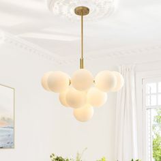 a chandelier hanging from the ceiling in a dining room with potted plants