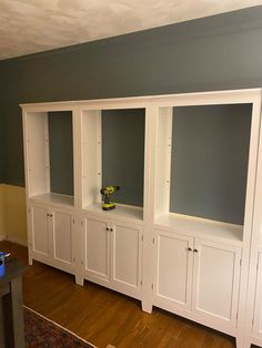 an empty room with white cabinets and wood floors