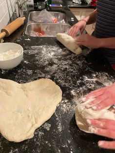 two hands are kneading dough on a counter