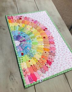 a multicolored quilt is laying on the floor next to a wooden table top