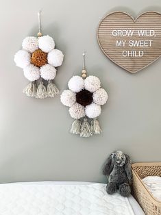 two white flowers are hanging on the wall next to a teddy bear and a heart