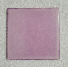 a square purple plate sitting on top of a white carpet