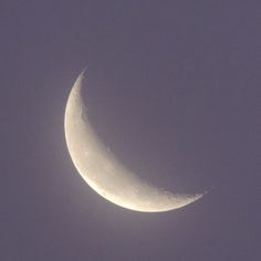 the crescent moon is seen against a cloudy sky