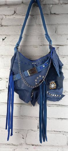 This spectacular design is made of cowhide, electric blue color and soft fur. With outer pockets and short handle to hang on the shoulder or crossed, not adjustable. Main clasp closure, cotton inner lining, with camouflage print. Main belt, with adjustable buckle. Rivets, patches and decorative chains, which complement the rock style. Punk Leather Bag For Festivals, Blue Tote Hobo Bag For Festivals, Handmade Blue Hobo Shoulder Bag, Blue Bags With Adjustable Strap For Festival, Blue Festival Shoulder Bag With Adjustable Strap, Blue Tote Shoulder Bag For Festivals, Blue Shoulder Bag With Adjustable Strap For Festival, Blue Bohemian Leather Bag, Bohemian Blue Leather Bag