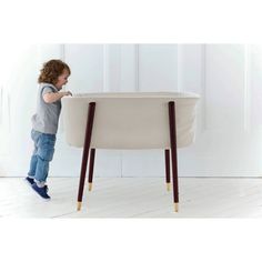 a little boy standing next to a white table