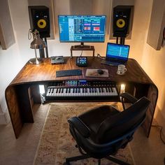 a computer desk with two monitors, keyboard and speakers on it in front of a wall