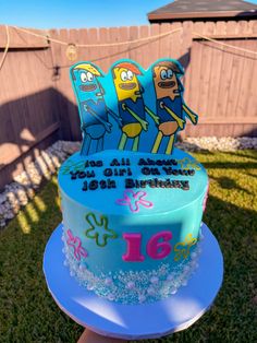 a birthday cake with cartoon characters on it sitting in the grass near a backyard fence