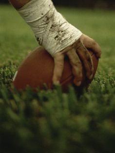 a book cover with an image of a hand on top of a football in the grass