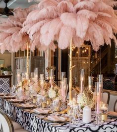 the table is set with pink feathers and candles