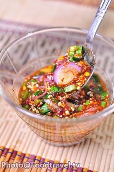 a glass bowl filled with food on top of a wooden table next to a bamboo mat