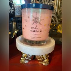 a candle that is sitting on top of a marble stand with the words cosmic stardust in it