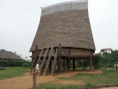 an old wooden structure with a thatched roof in the middle of a grassy area