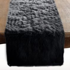 a table with a black and grey fur runner on it's edge next to a wooden bench