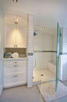 a bathroom with white cabinets and glass shower doors