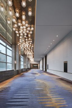 an empty room with lights hanging from the ceiling and carpeting on the floor in front of large windows