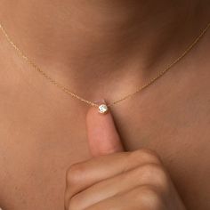 a close up of a person wearing a gold necklace with a diamond on the middle