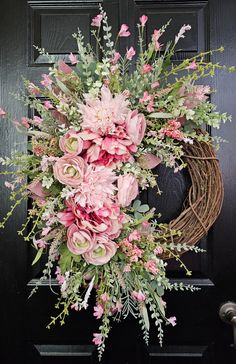 a wreath with pink flowers and greenery hangs on the front door's black door