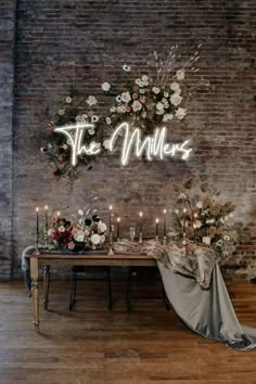 a table with flowers and candles on it in front of a brick wall that says the millers