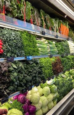 an assortment of vegetables are on display in a grocery store's produce section, including lettuce, broccoli, cabbage and radishes