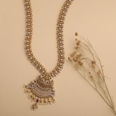 Description: A sculptural form of an antique necklace takes inspiration from the temples of India and translates it into a dressy pair to adorn. The hue of antique gold adds up a sparkle with the CZ stones along with the pearl drops at the base enhance the beauty of the piece. Making its presence felt with any outfit this one is worth making an on-trend statement. Details & Specifications: Materials used: Brass Alloy with Antique Plating Weight – Necklace 84 gm, Earrings 25 gm Length – Necklace Handmade Temple Style Long Necklace, Traditional Gold Long Beaded Necklace, Antic Gold Long Necklace, Vintage Antique Gold Long Necklace, Gold Bollywood Temple Long Necklace, Antique Necklace, Gold Polish, Pearl Drop, Cz Stone