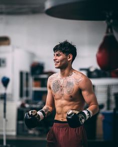 a shirtless man with boxing gloves on his chest and hands in front of him