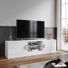 a flat screen tv sitting on top of a white entertainment center in a living room