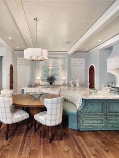 a large kitchen with an island and dining table surrounded by chairs that are upholstered