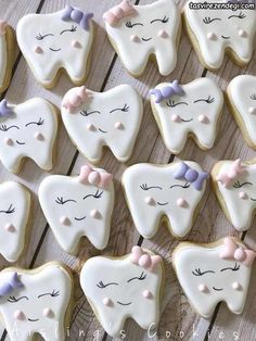 decorated cookies arranged in the shape of teeth with bows on them are sitting on a wooden table