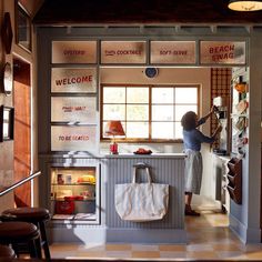 a woman standing in the doorway of a kitchen with lots of signs on the wall