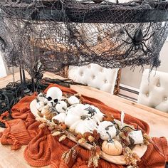 a wooden table topped with white pumpkins and other halloween decorations on top of it