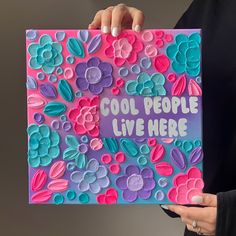 a woman holding up a card with flowers on it that says cool people live here