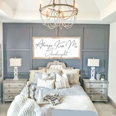 a large bed sitting under a chandelier next to a wall with writing on it